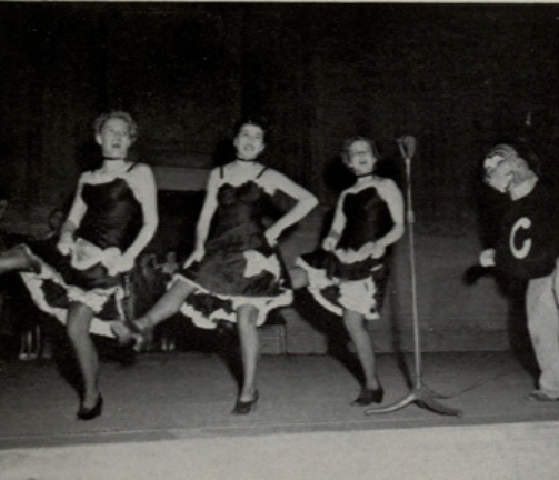 Archival scan: Oski alongside a line of dancers. Photo credit: Photographer/artist uncredited in supplied scan.