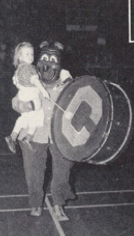 Archival scan: Oski beside a large Cal bass drum and a child. Photo credit: Photographer/artist uncredited in supplied scan.
