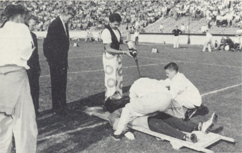 Archival scan: Oski lying on a stretcher during a sideline performance. Photo credit: Photographer/artist uncredited in supplied scan.