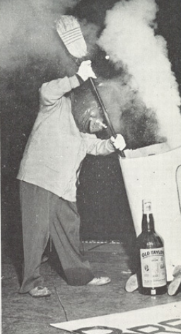 Archival scan: Oski stirring a steaming container with a large paddle. Photo credit: Photographer/artist uncredited in supplied scan.