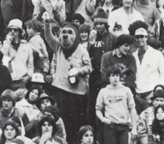 Archival scan: Oski holding a cup in a stadium crowd. Photo credit: Photographer/artist uncredited in supplied scan.
