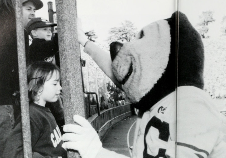Archival scan: Oski greeting children through a fence. Photo credit: Photographer/artist uncredited in supplied scan.